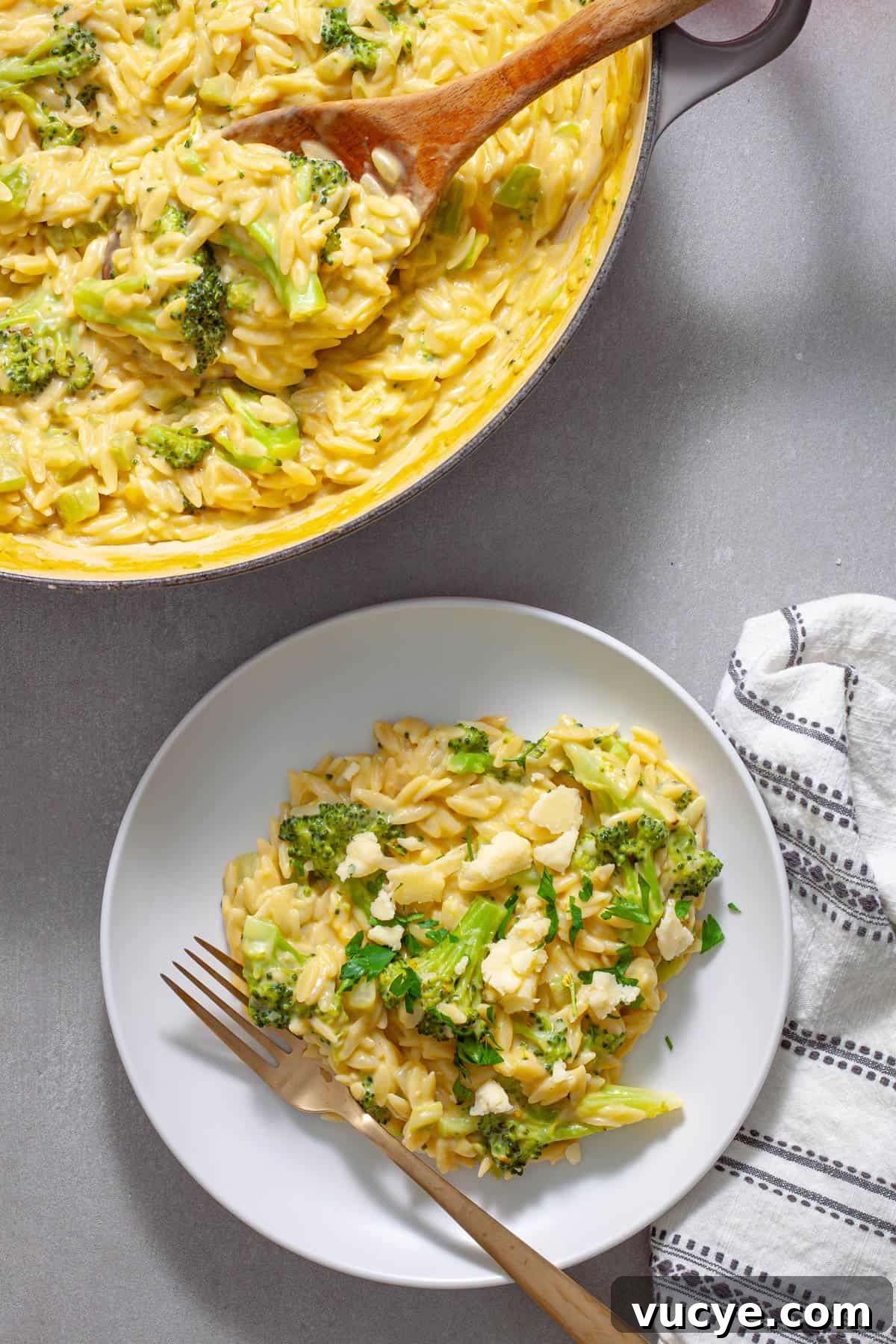 Creamy Broccoli Orzo Pasta with Garlic and Parmesan 2 A serving of creamy broccoli orzo on a white plate with a pot of more off to the side.