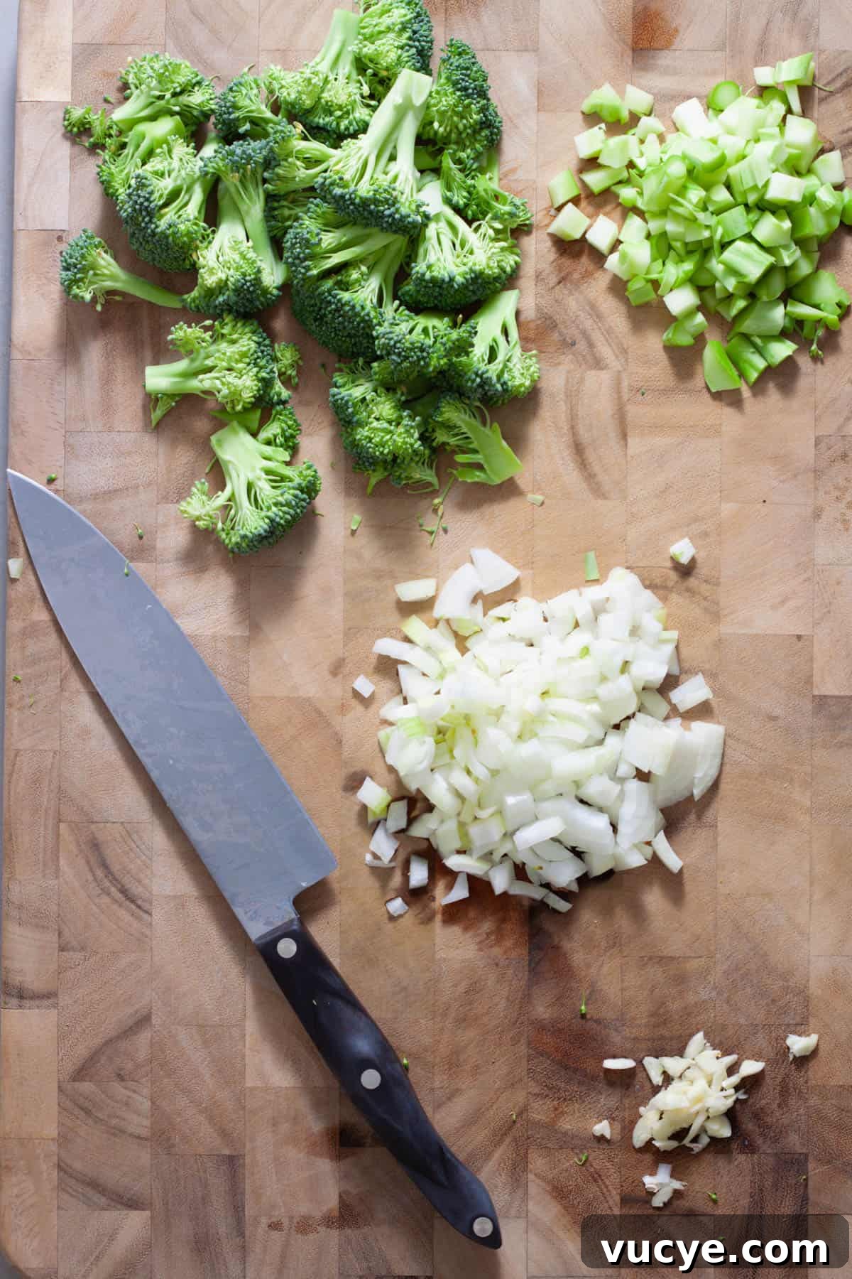 Creamy Broccoli Orzo Pasta with Garlic and Parmesan 4 A diced onion and minced garlic on a cutting board with a head of broccoli diced and the florets chopped.