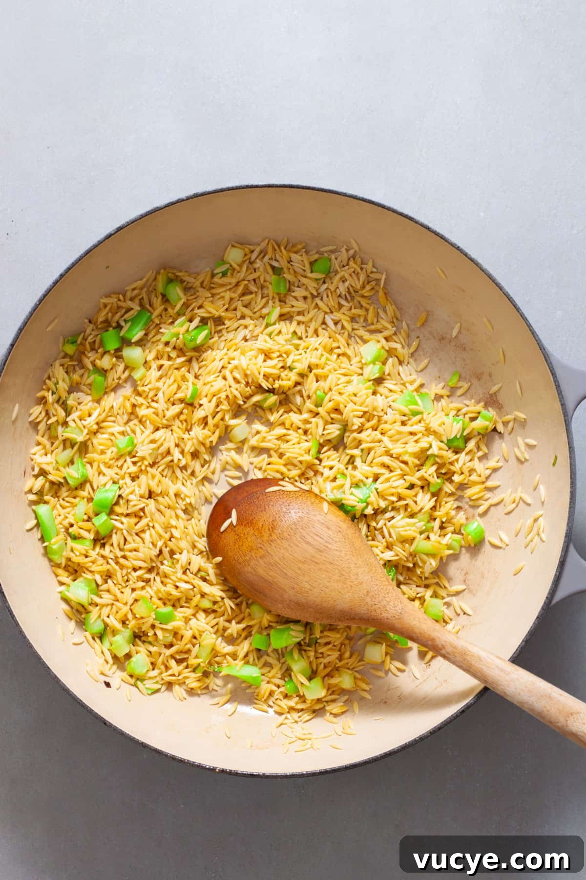 Creamy Broccoli Orzo Pasta with Garlic and Parmesan 6 Orzo and chopped broccoli stem in a large skillet cooking in oil.