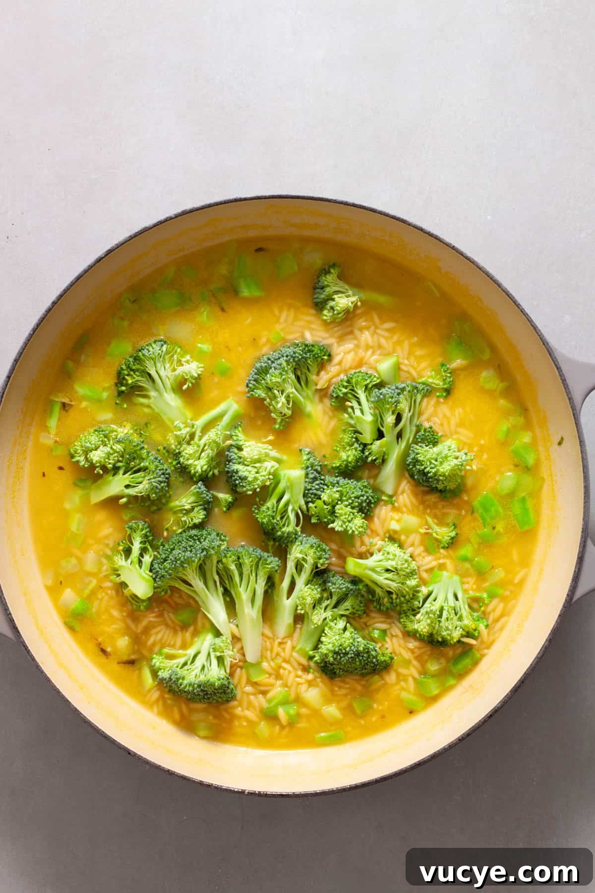 Creamy Broccoli Orzo Pasta with Garlic and Parmesan 7 A large skillet with broccoli and orzo cooking in vegetable broth.