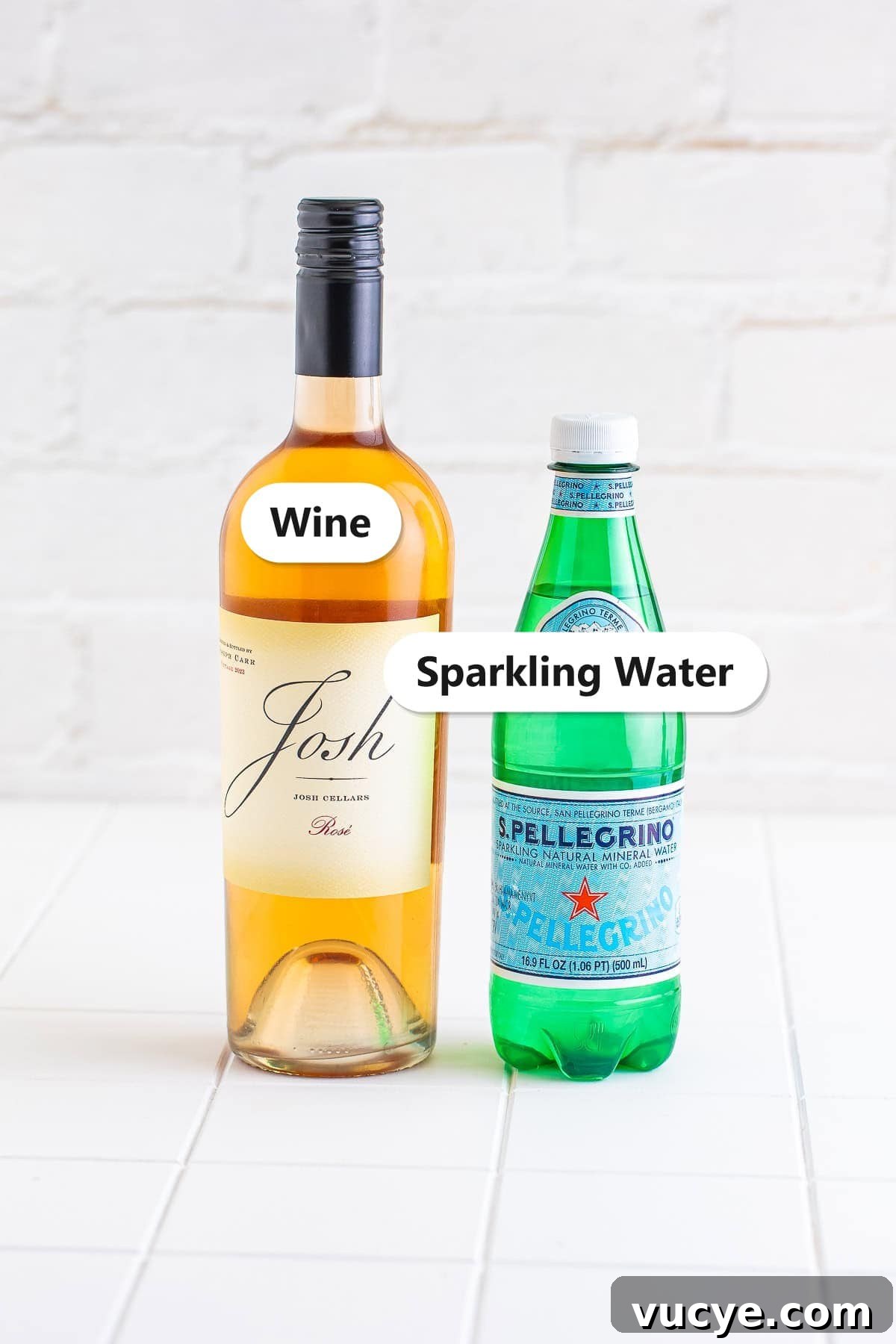 Labeled ingredients for a wine spritzer including a bottle of wine and sparkling water.