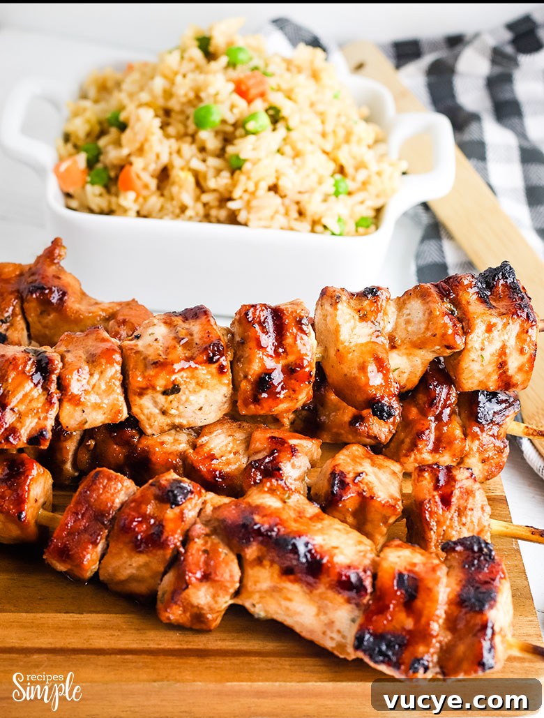 Asian Grilled Pork Kabobs Skewers on wood platter with fried rice in background