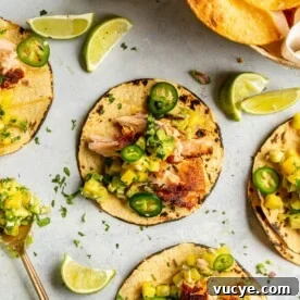 Maple Teriyaki Salmon Rice Bowls with Sesame & Scallions 6 Grey tabletop with three salmon tacos on charred corn tortillas garnished with pineapple salsa, jalapeno, and cilantro.