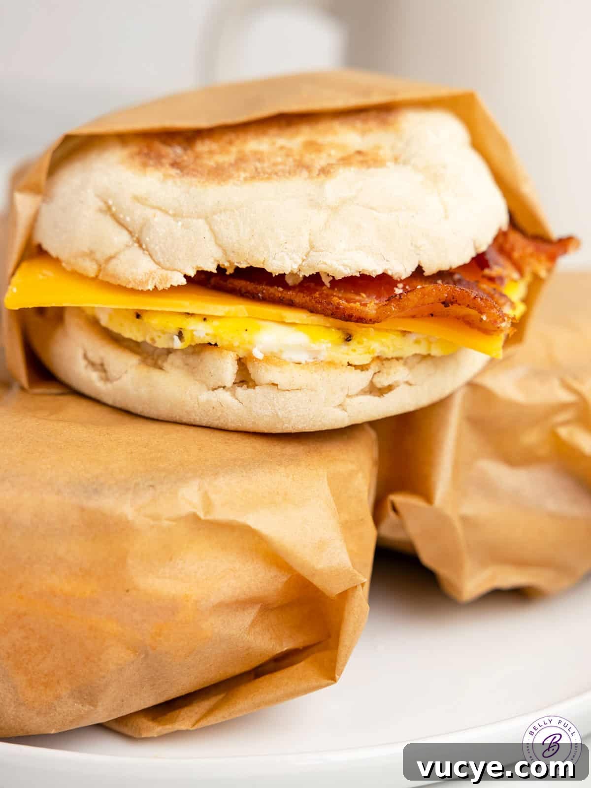 Made with egg, cheese, and breakfast meat on an English muffin, these Freezer Breakfast Sandwiches are perfect for busy mornings. Three make ahead breakfast sandwiches, two wrapped in parchment paper