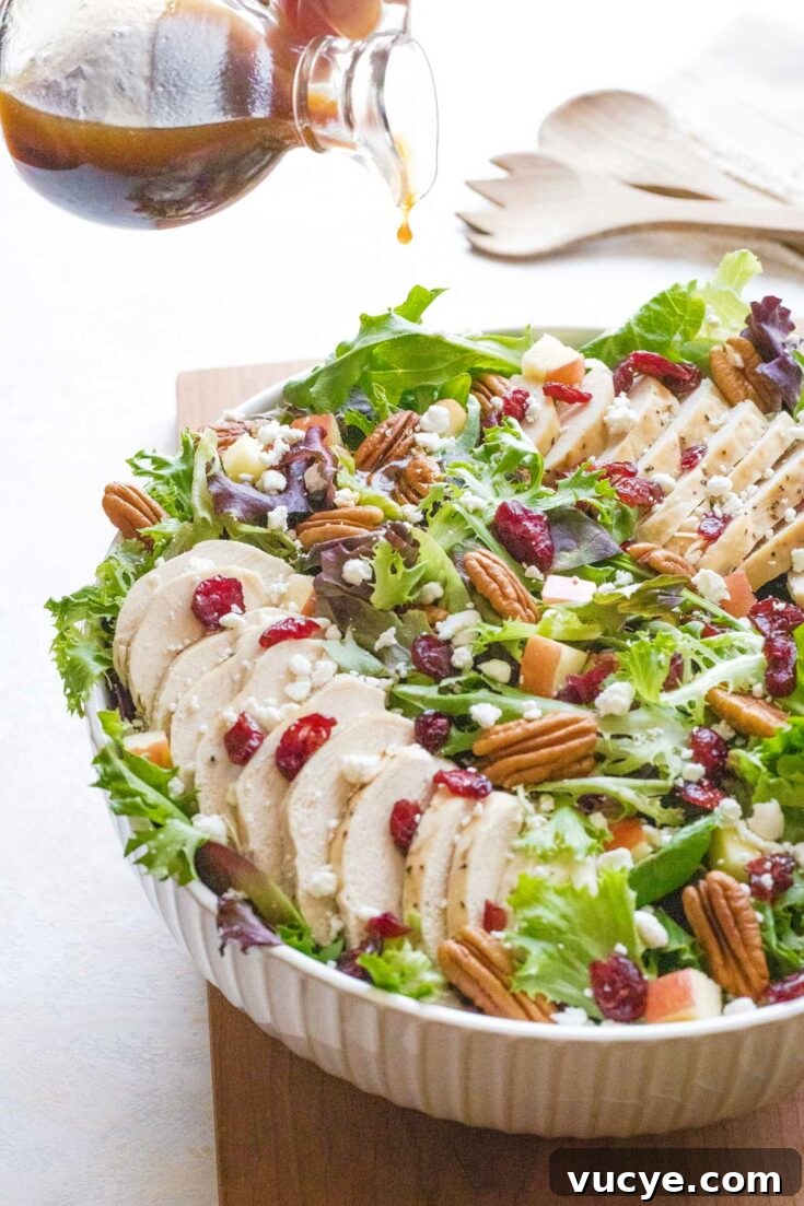 Pouring dressing onto pecan chicken salad in a serving bowl.