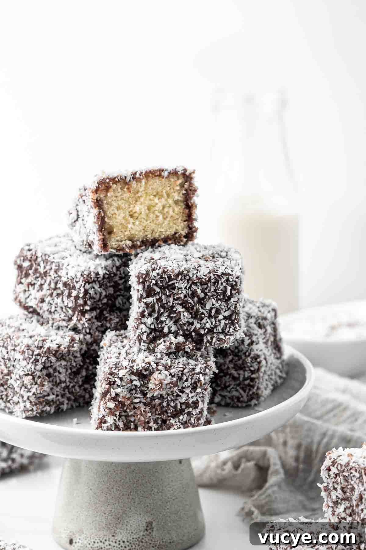 Classic Australian Lamington Recipe: Moist Sponge Cakes with Chocolate & Coconut 9 A stack of lamingtons on a cake stand.