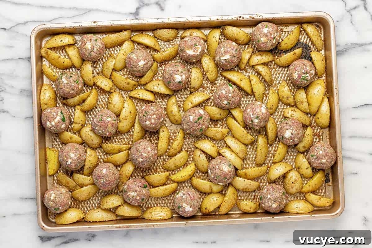 Greek-Style Sheet Pan Meatballs with Roasted Potatoes 6 Raw meatballs and quartered potatoes on a large sheet pan.