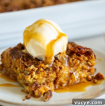 A slice of pumpkin dump cake with pecans, topped with vanilla ice cream and drizzled with caramel
