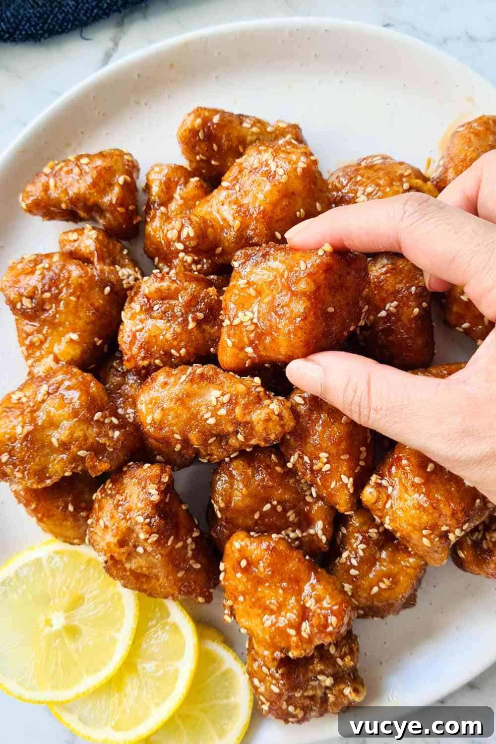 A piece of crispy chicken piece being picked up by two fingers