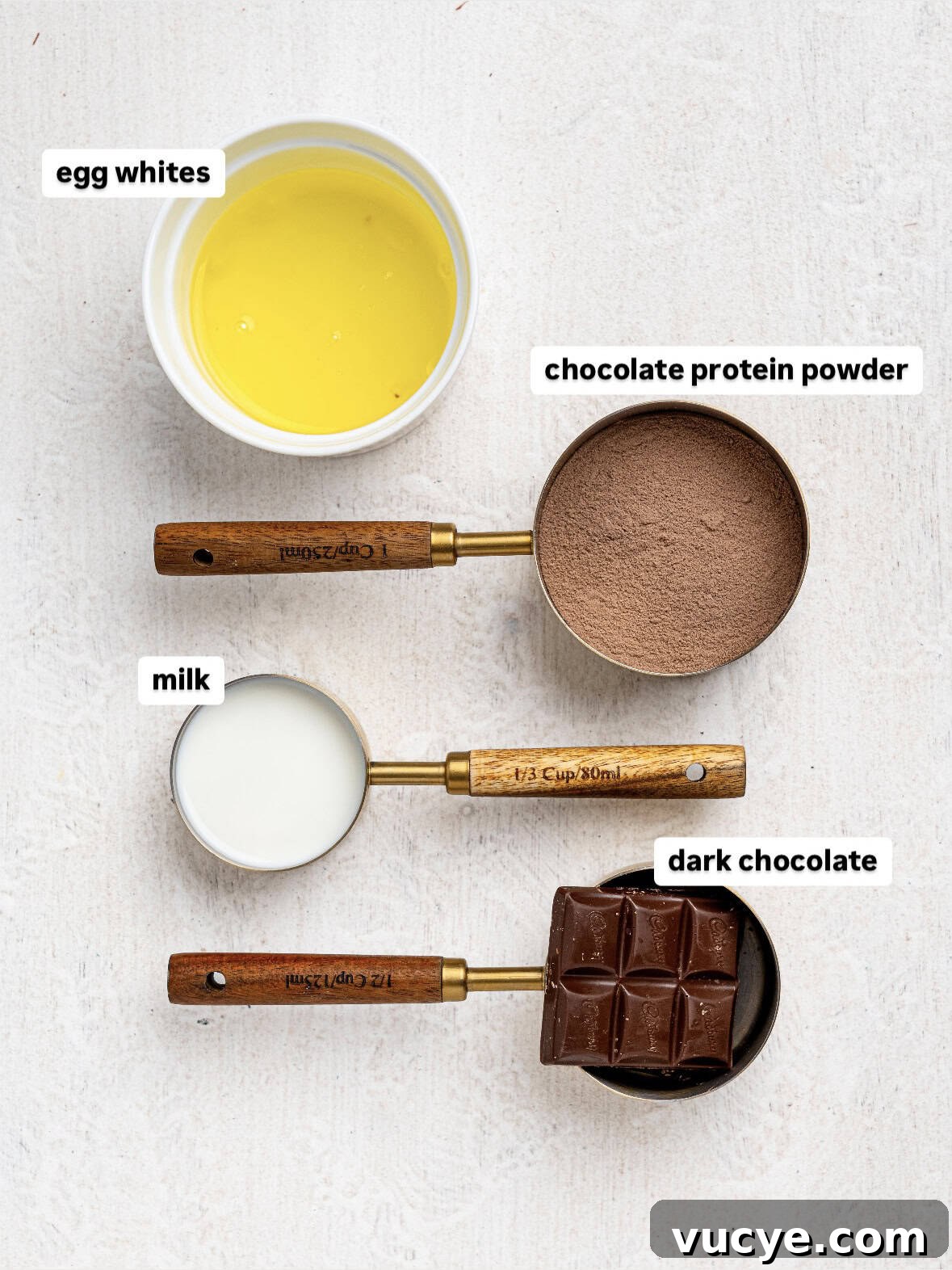 Ingredients needed to make protein chocolate mousse: egg whites, chocolate protein powder, milk, and dark chocolate.