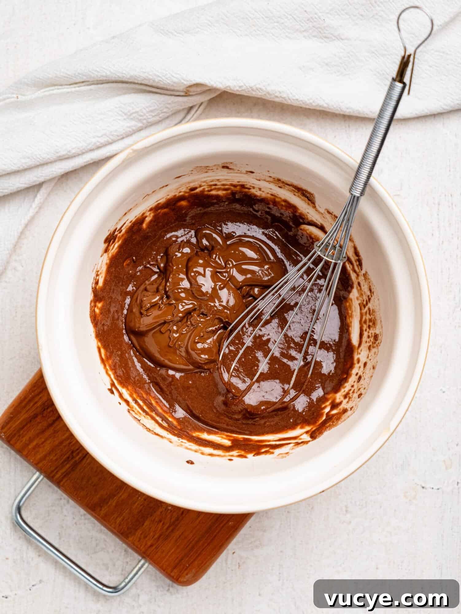 Melted dark chocolate, protein powder and milk in a mixing bowl.