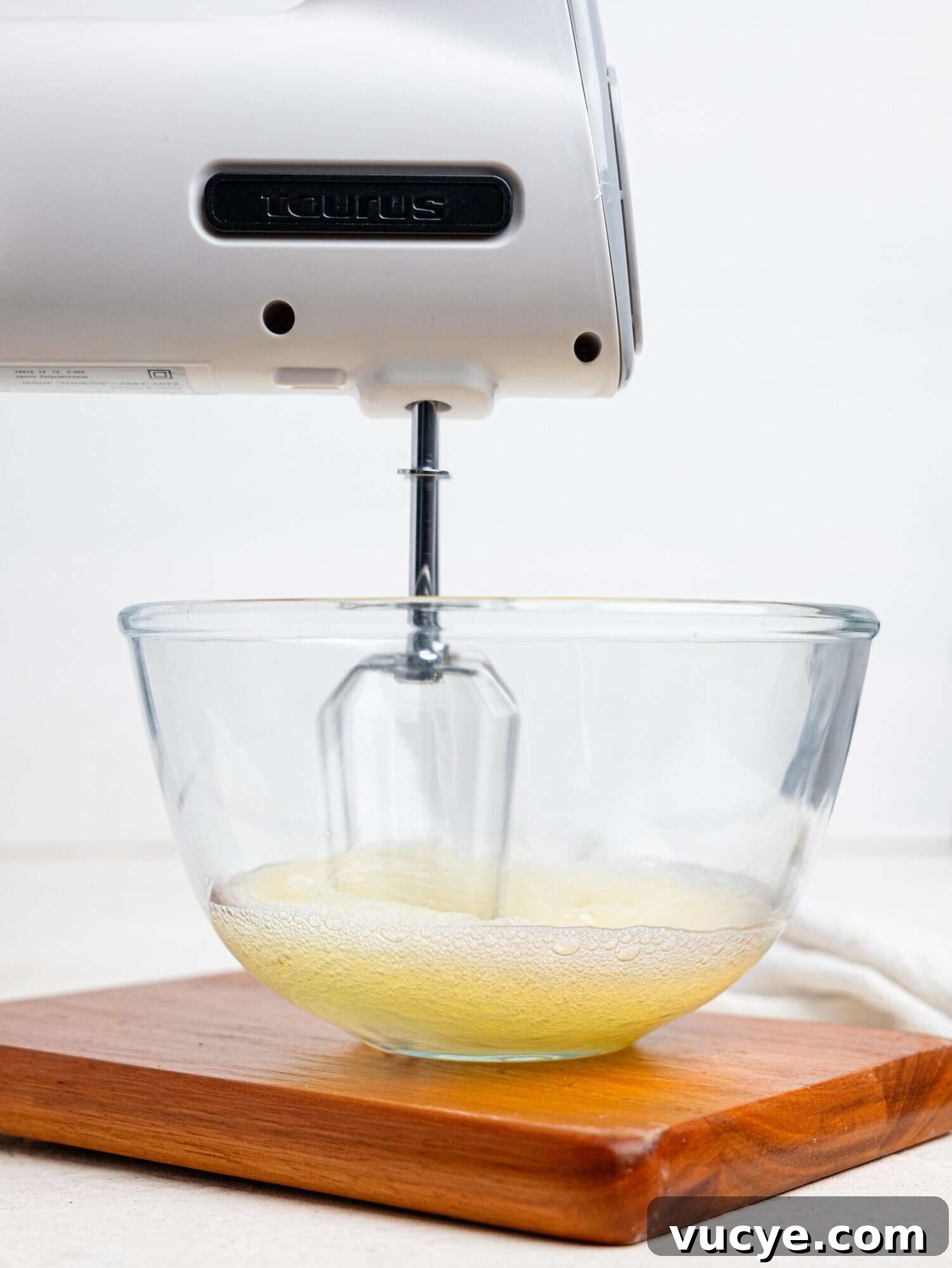 Egg whites being whipped in a glass bowl.