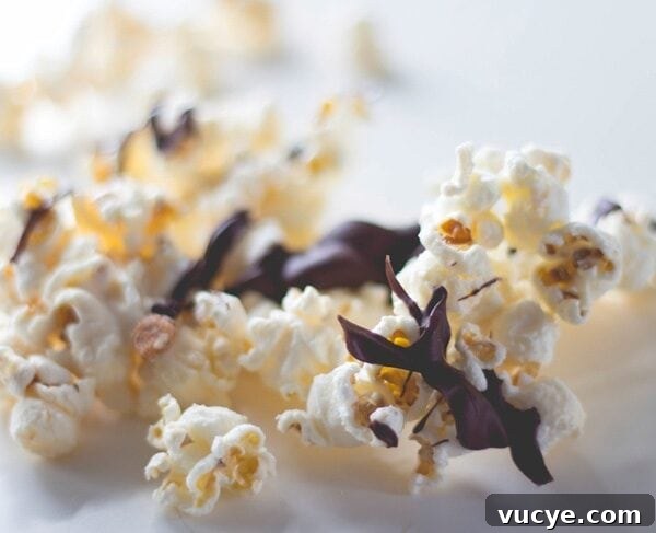 Kernels of popcorn sitting on white surface covered with chocolate