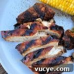 Sweet and Smoky Grilled Chicken Recipe for Weeknight Meals 18 Sliced Sweet & Smoky Chicken and an ear of corn on a white plate.