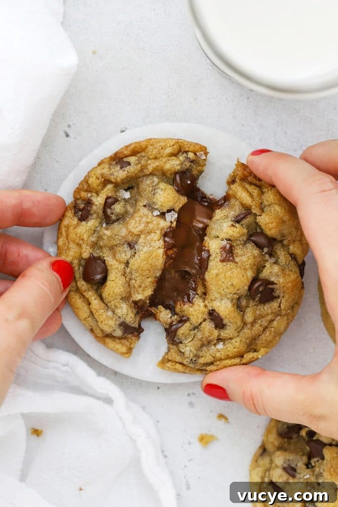 Pulling apart a gluten-free Nutella chocolate chip cookie, revealing the gooey nutella center
