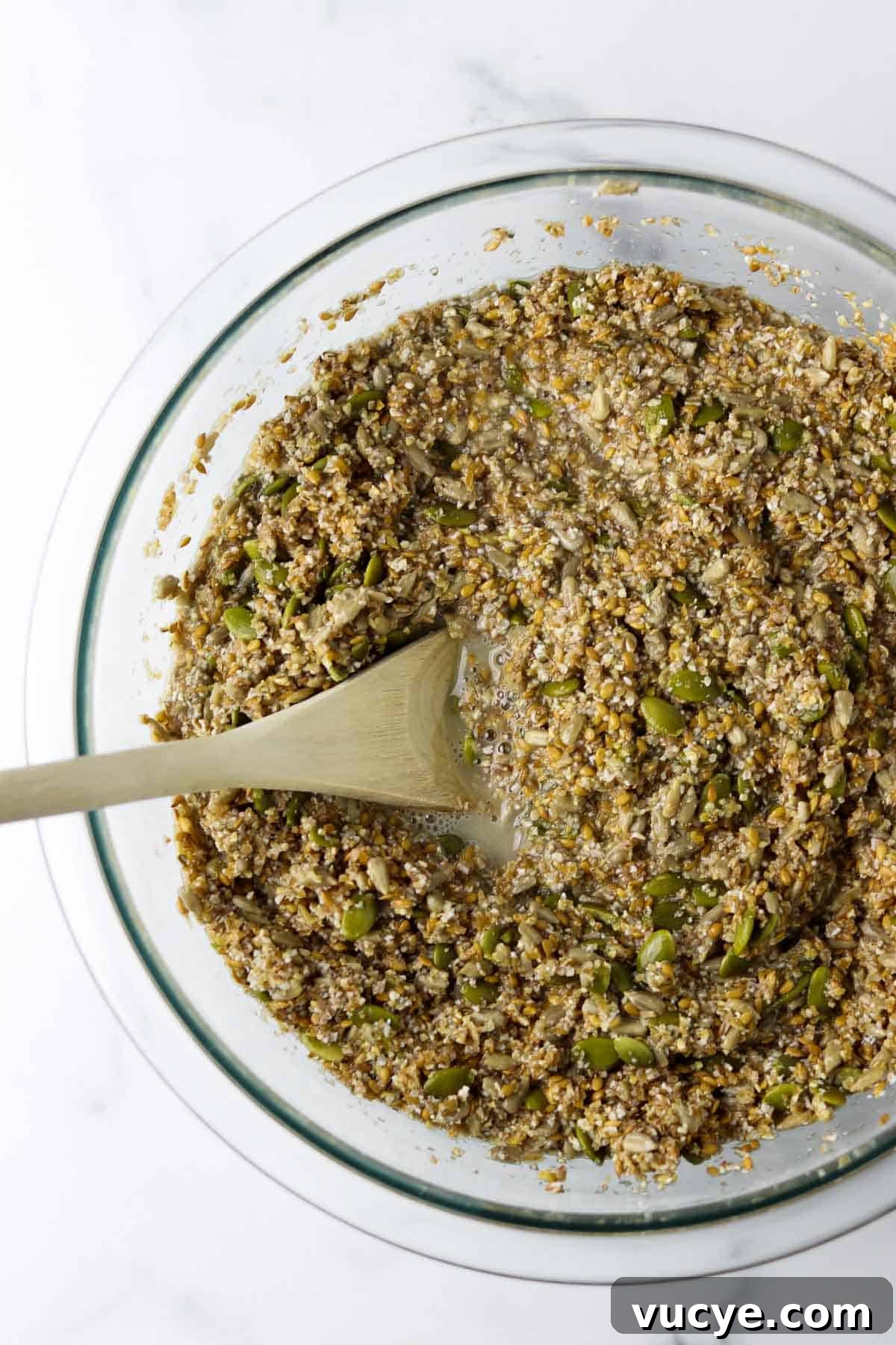 Seeds and water in a glass bowl with a wooden spoon.