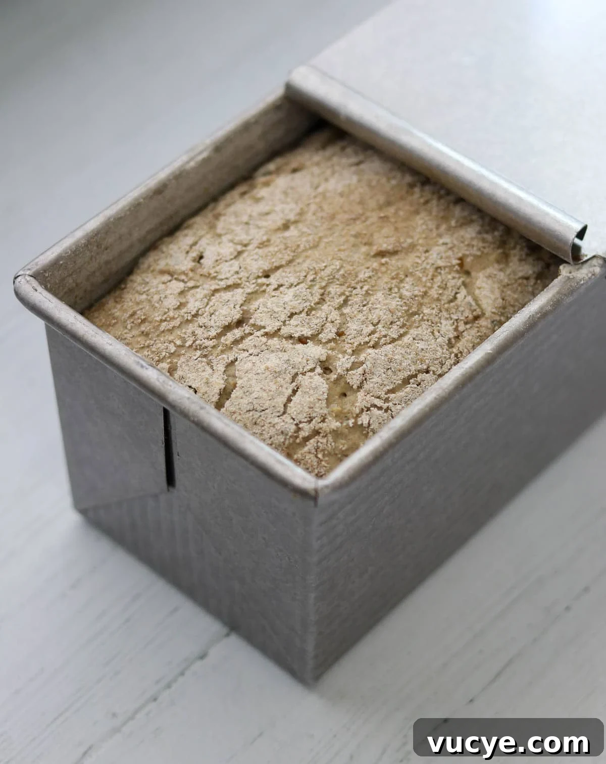 Danish Rye Bread rising in a pullman pan with the lid partially removed.