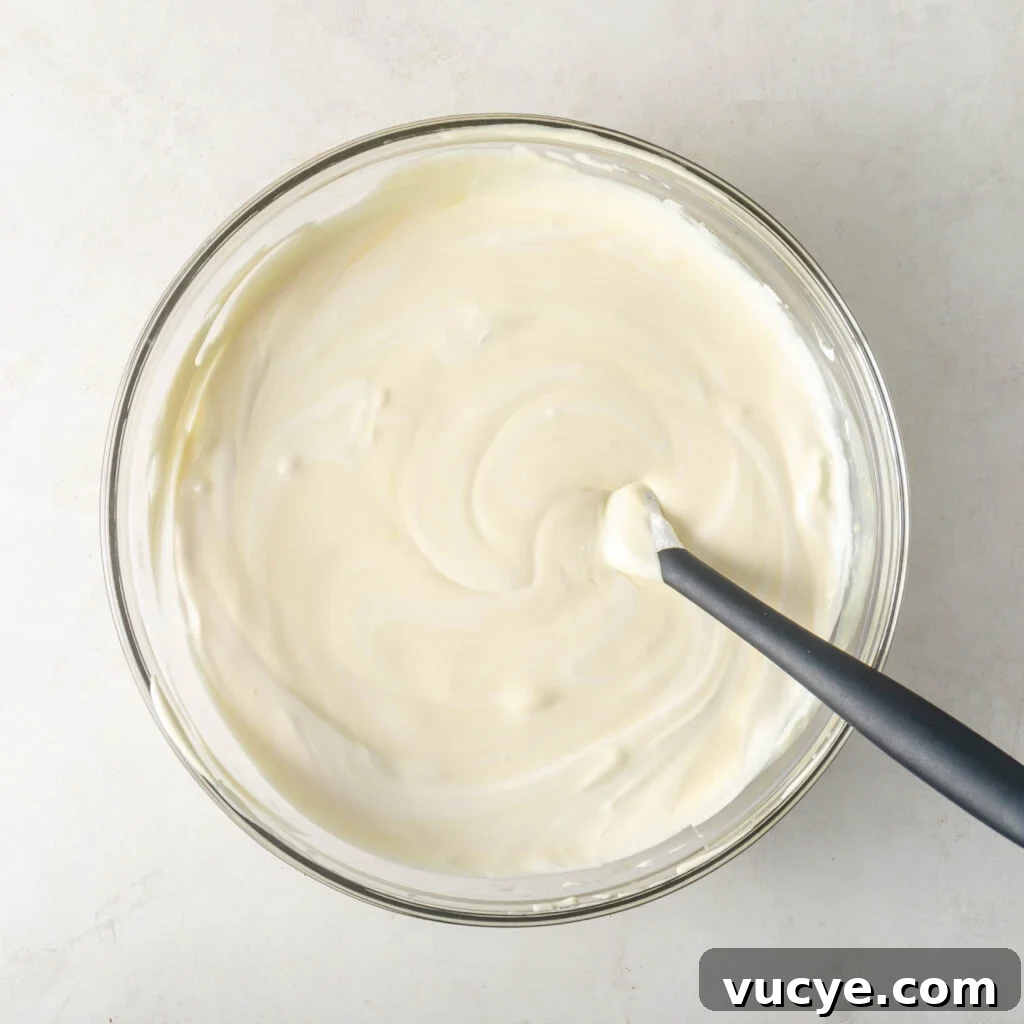 completely combined pudding, milk, condensed milk, and cool whip in a mixing bowl with a black spatula