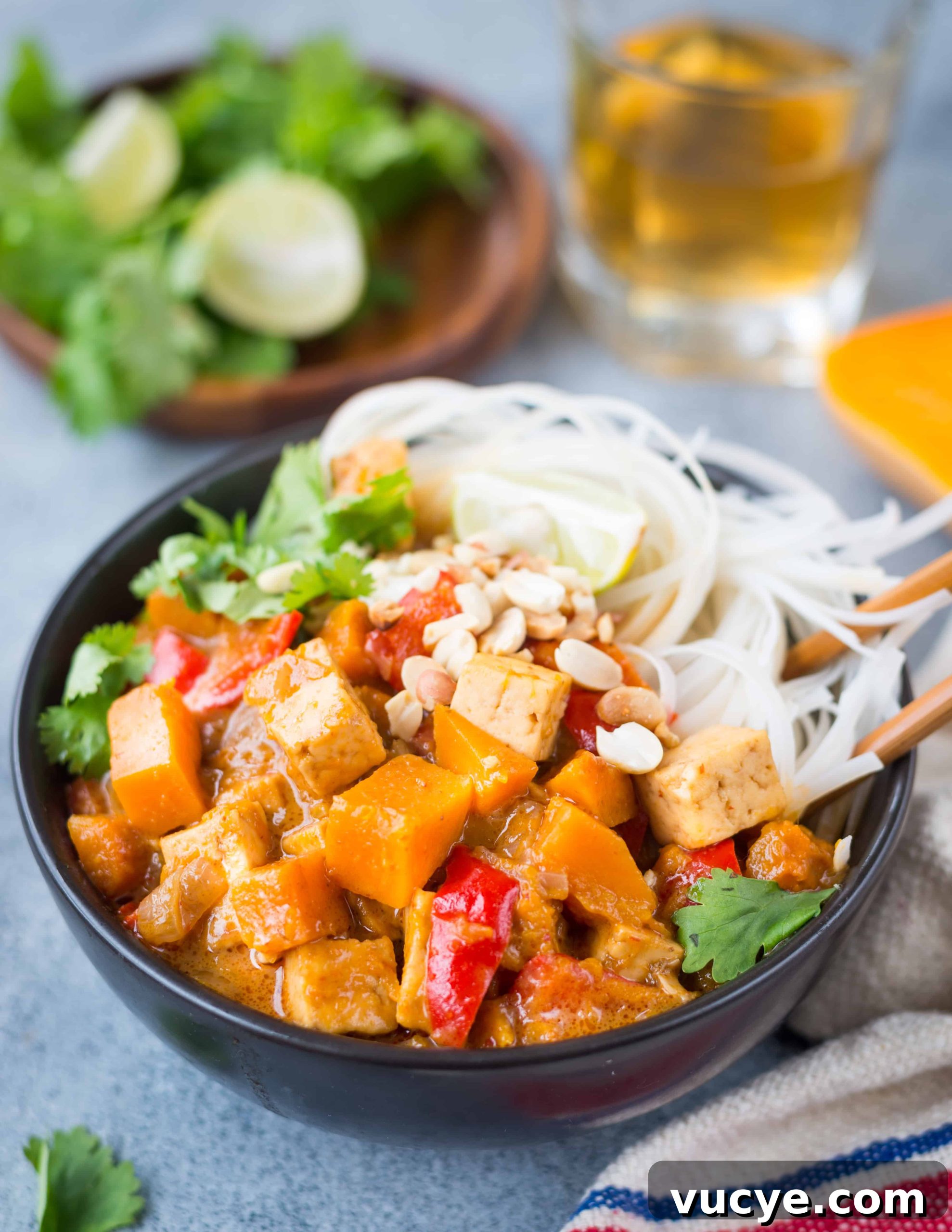 Side view of butternut squash curry served in a bowl with noodles.