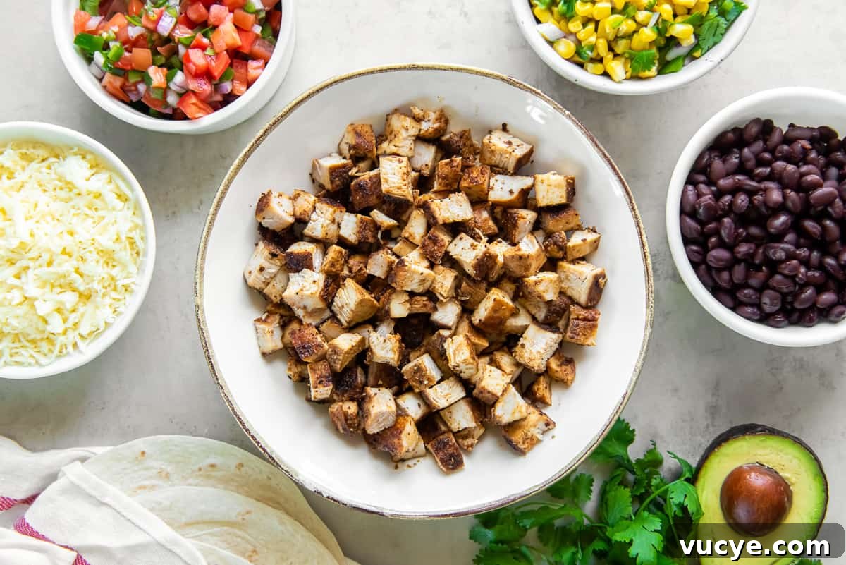 Smoky Chipotle Chicken Recipe: Juicy Grilled Chicken with Sauce 5 A bowl of copycat Chipotle Chicken surrounded by bowls filled with black beans, salsa, and other ingredients.