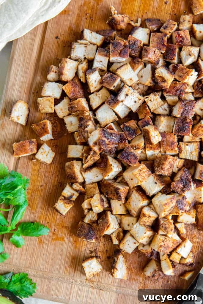 Smoky Chipotle Chicken Recipe: Juicy Grilled Chicken with Sauce 8 A top down shot of cooked, cubed chicken on a cutting board with cilantro sprigs.