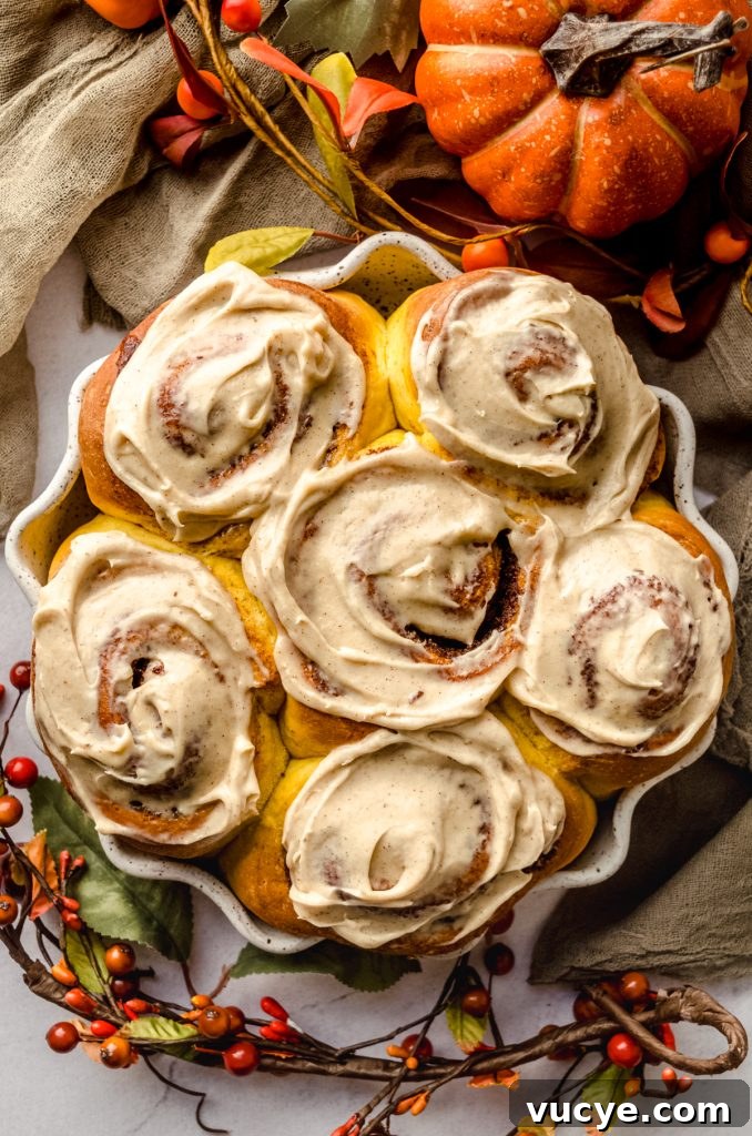 Aerial photo of pumpkin cinnamon rolls topped with maple cinnamon cream cheese frosting.