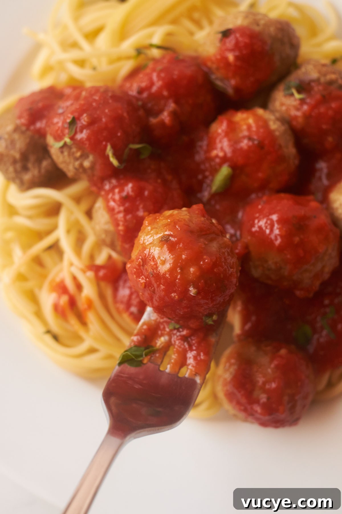 a fork removing one of the cooked frozen meatballs from a plate