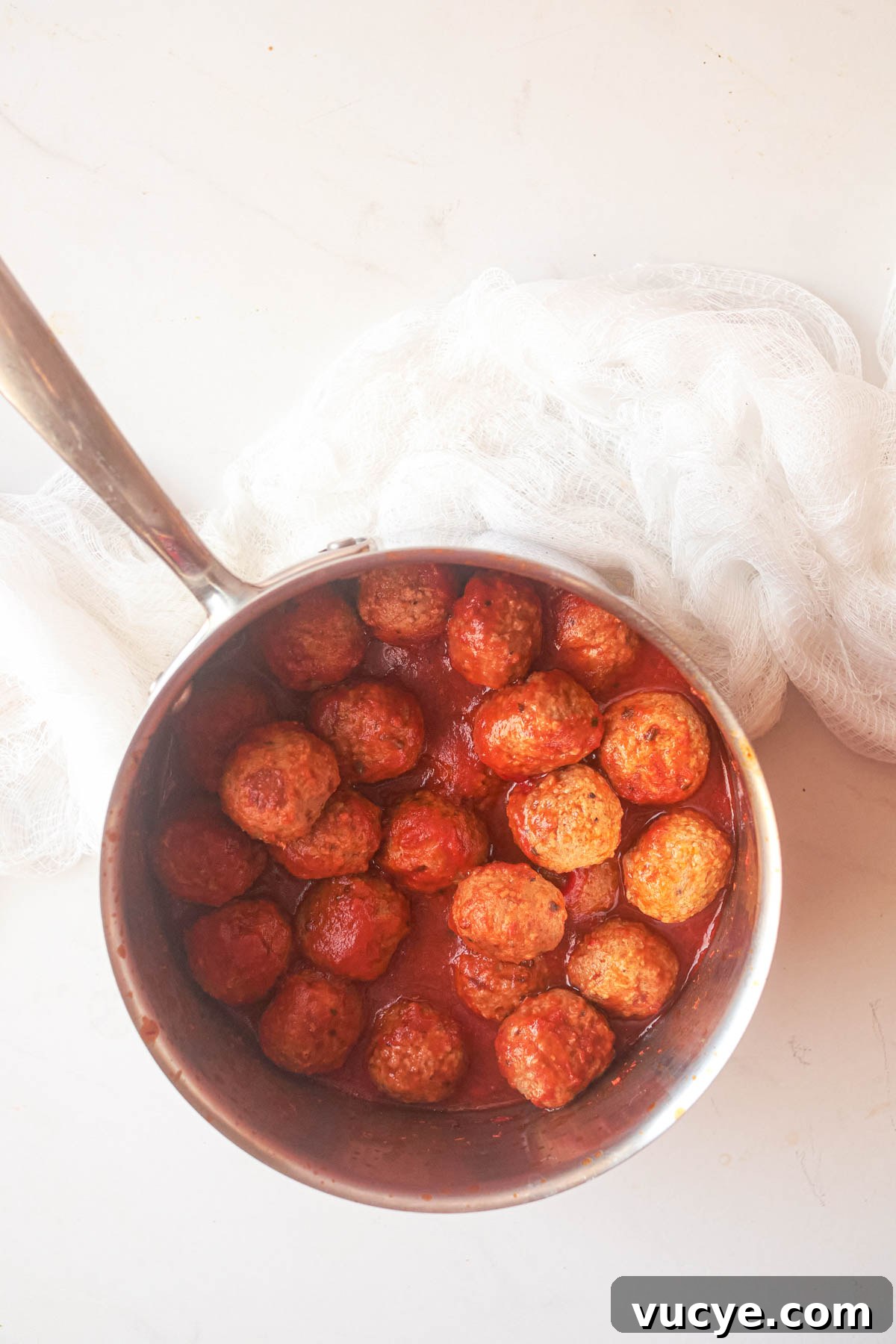 top down view of frozen meatballs in a pan with sauce as part of the how to cook meatballs on stovetop recipe