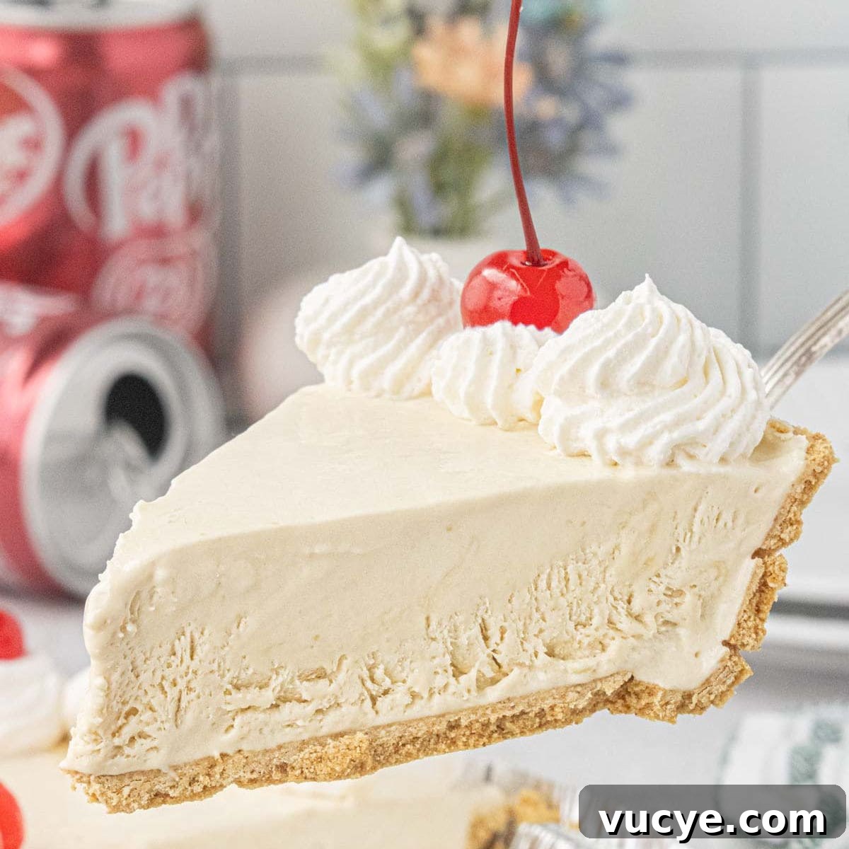Slice of Dr Pepper icebox pie with graham cracker crust, whipped cream, and maraschino cherry lifted from the pie.