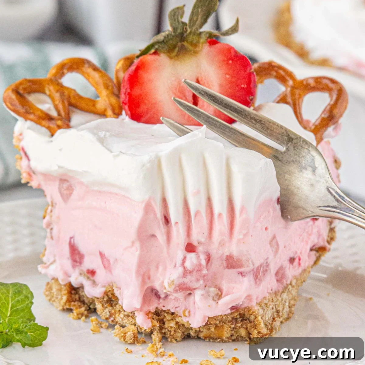 A slice of strawberry icebox pie being cut with a fork.