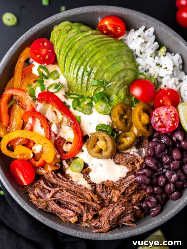 bowl with shredded beef, black beans, sauteed peppers and onions, tomatoes, cilantro lime rice and avocado