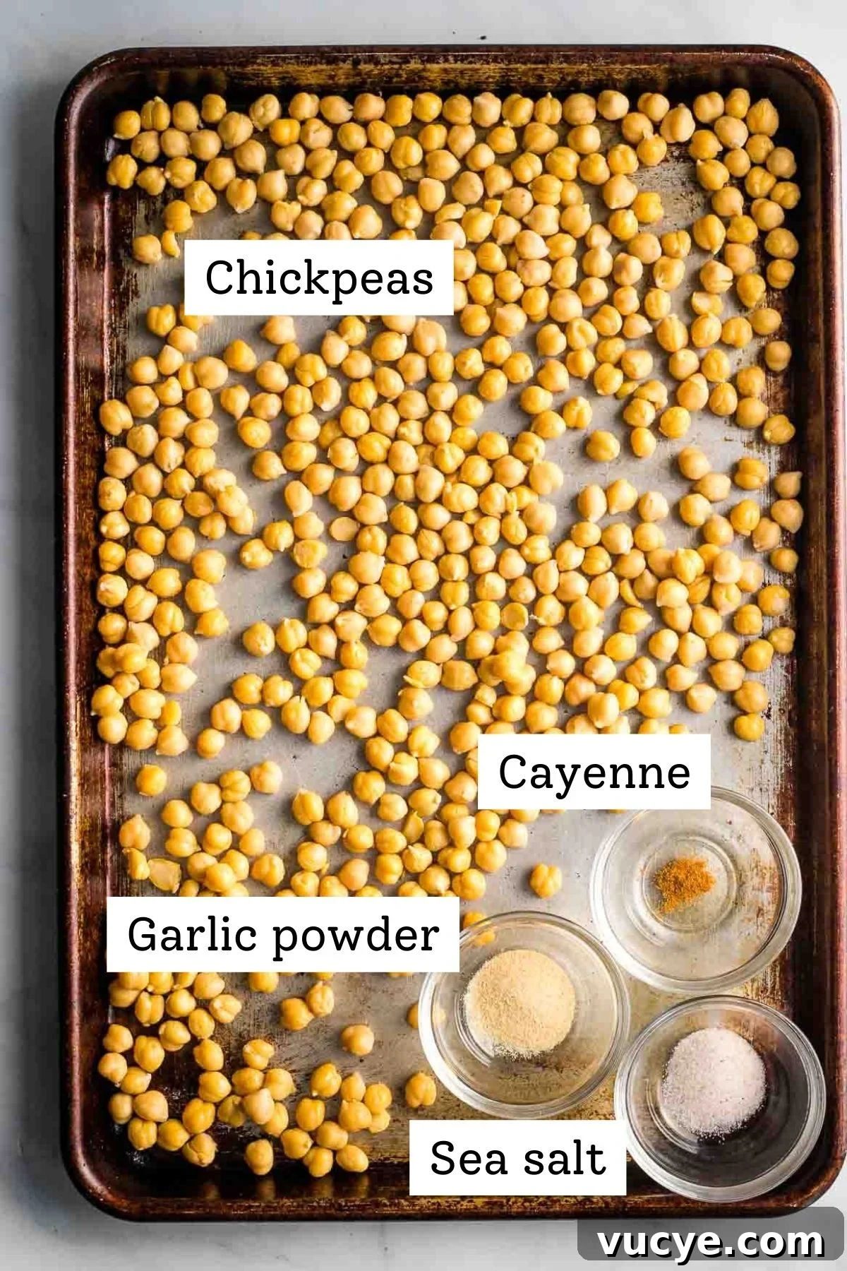 Labeled ingredients on a baking sheet: chickpeas, garlic powder, cayenne, sea salt.