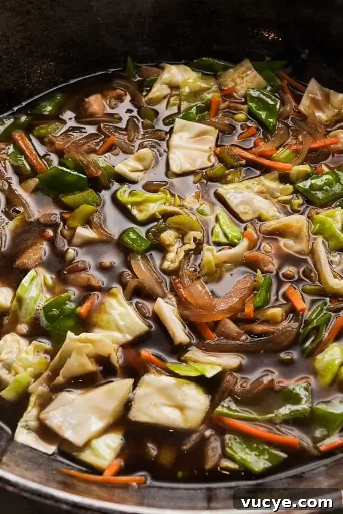 Veggies, broth, and soy sauce added to chicken sauté for pansit.