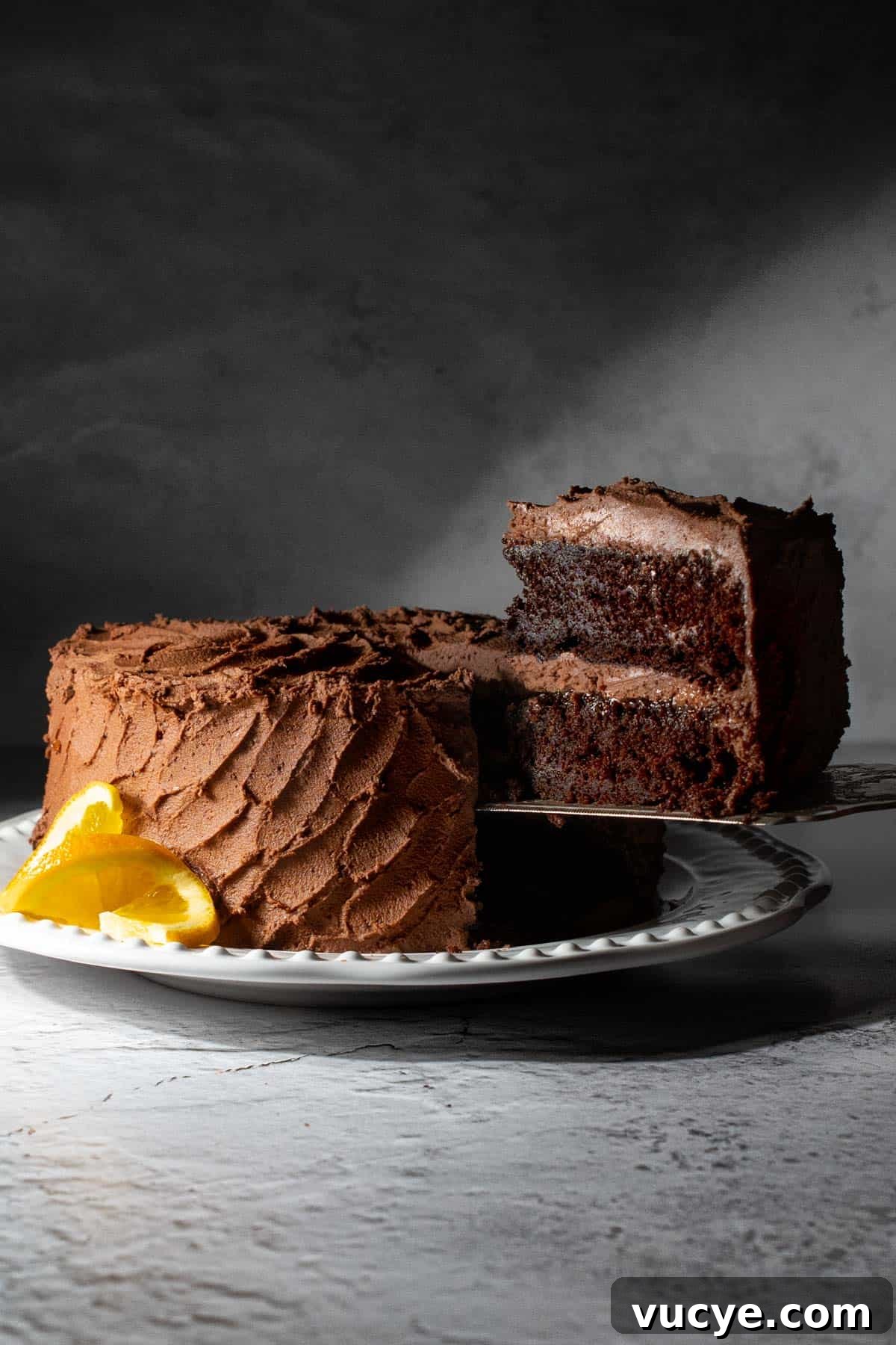 Chocolate orange cake on a white plate with a slice in the foreground.