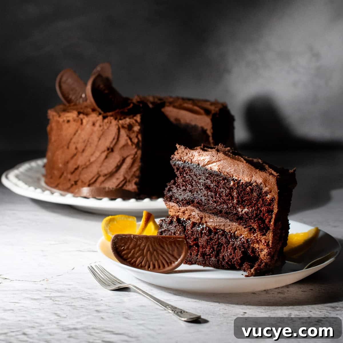 Chocolate orange cake on a white plate with a slice in the foreground.