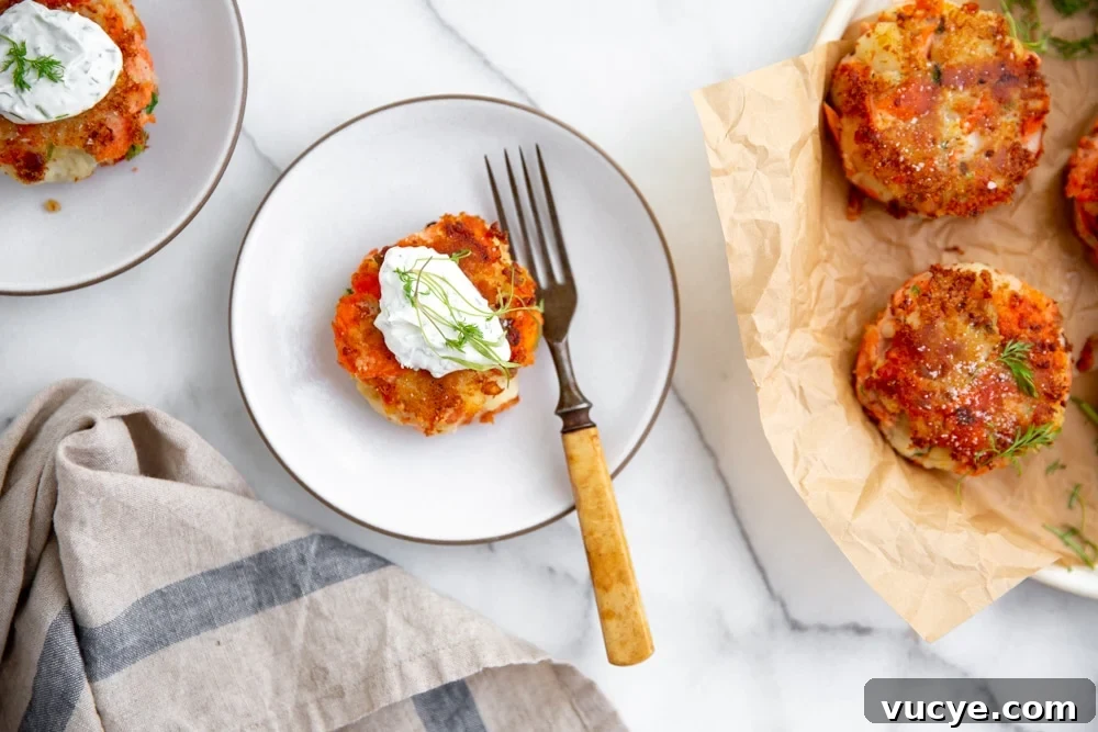 Crispy fish cake on a plate topped with yogurt sauce, with a fork alongside.
