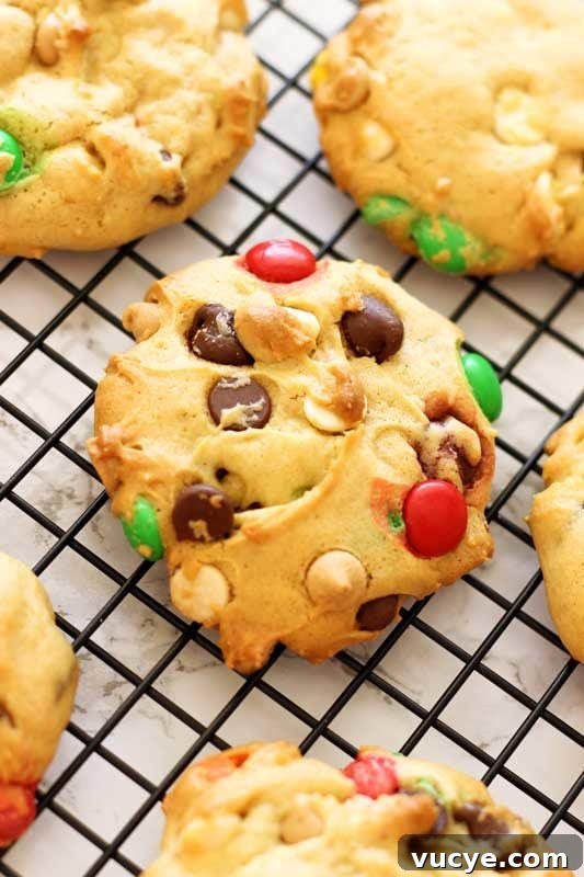 6 Boyfriend cookies cooling on a black wire cooling rack, topped with M&Ms and chocolate chips.