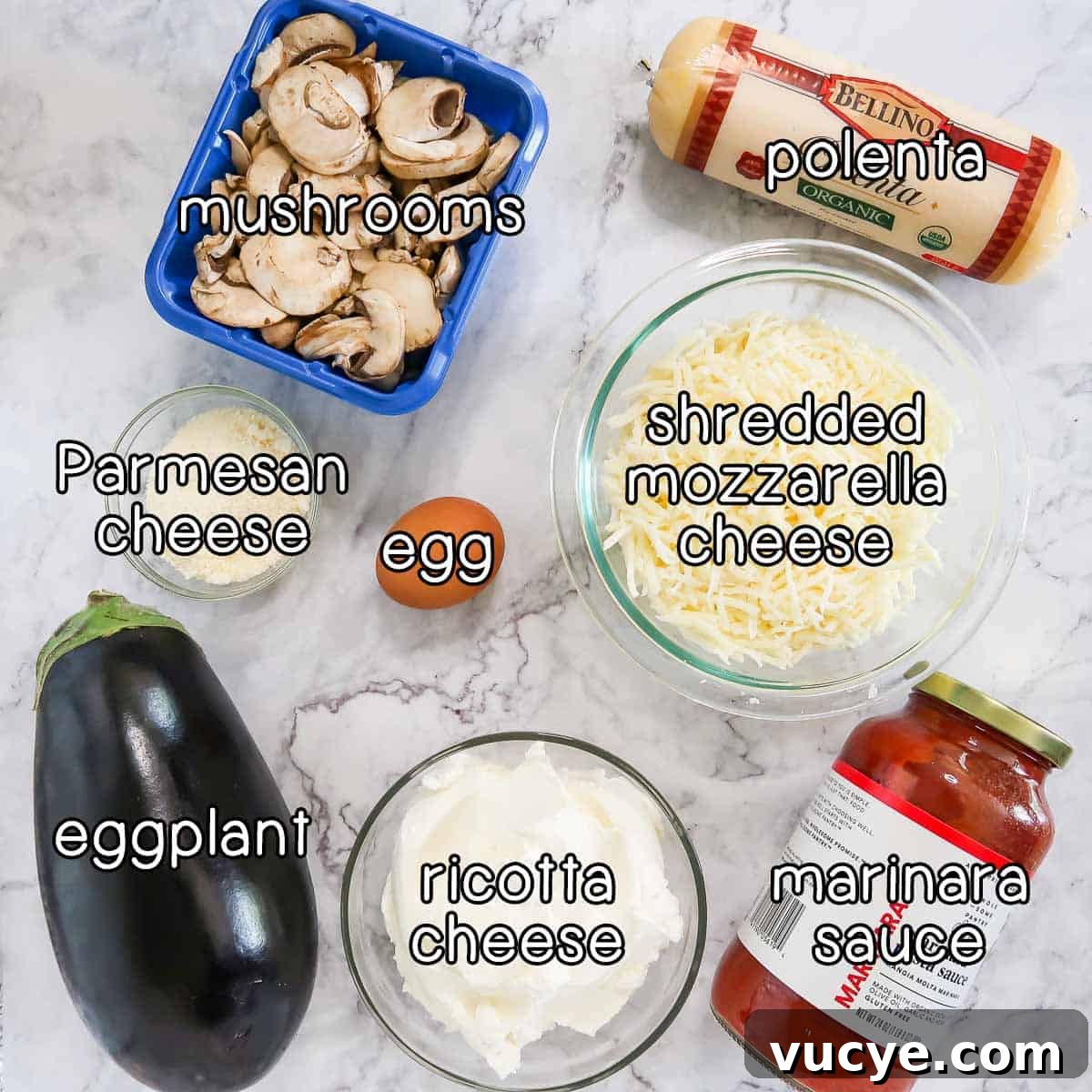 Overhead shot of ingredients - mushrooms, parmesan cheese, egg, polenta, shredded mozzarella cheese, marinara sauce, ricotta cheese, and eggplant.