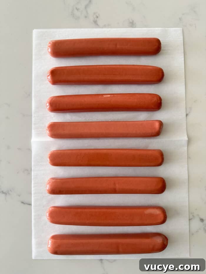 uncooked hot dogs removed from package on counter top.