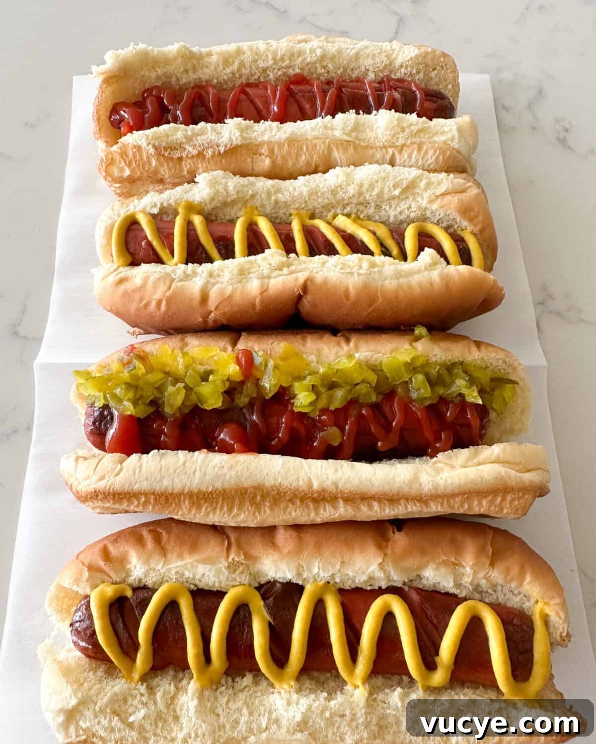hot dogs in buns with ketchup and mustard on counter